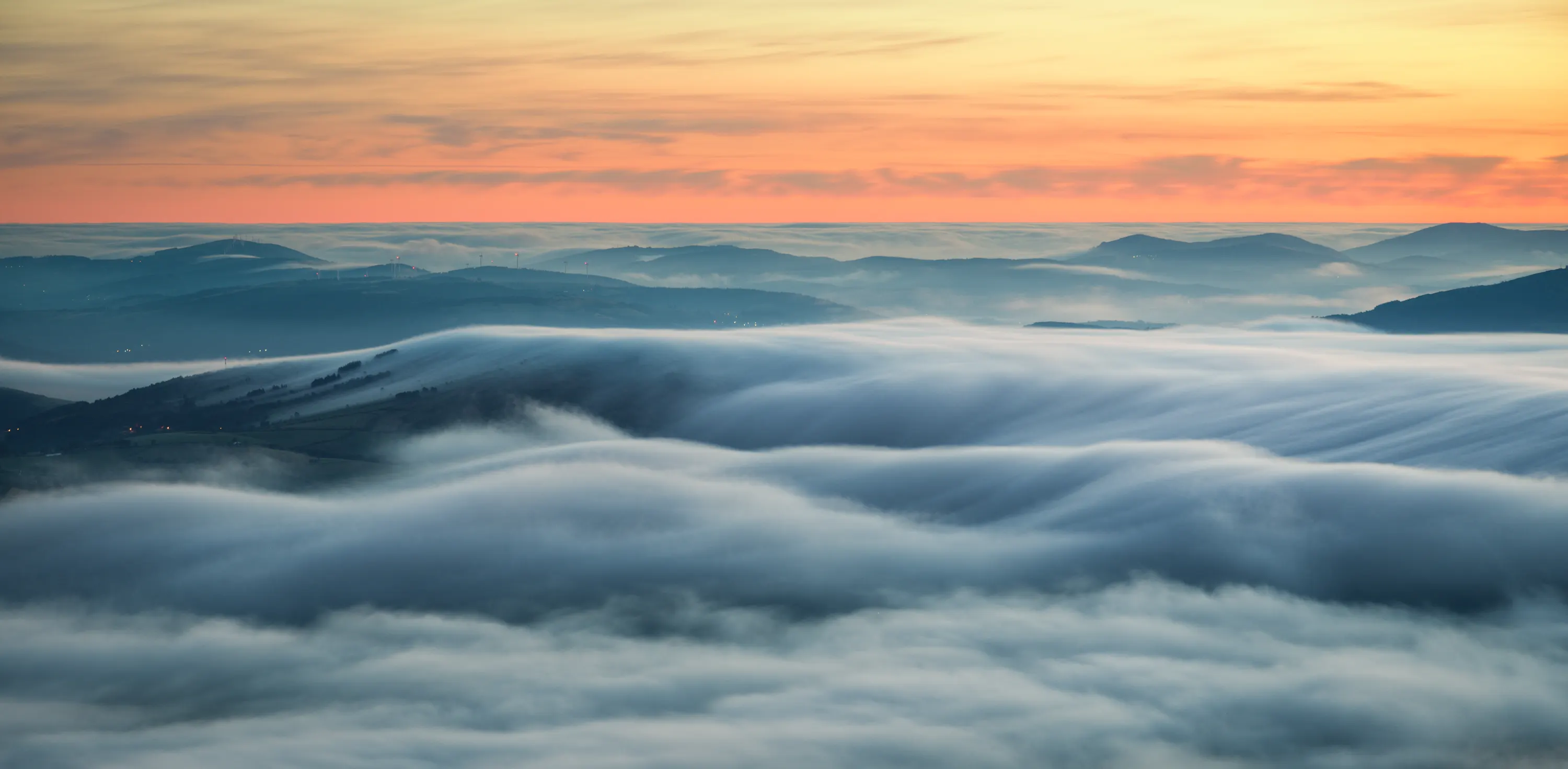 A valley filled with rolling cloud under a golden sky