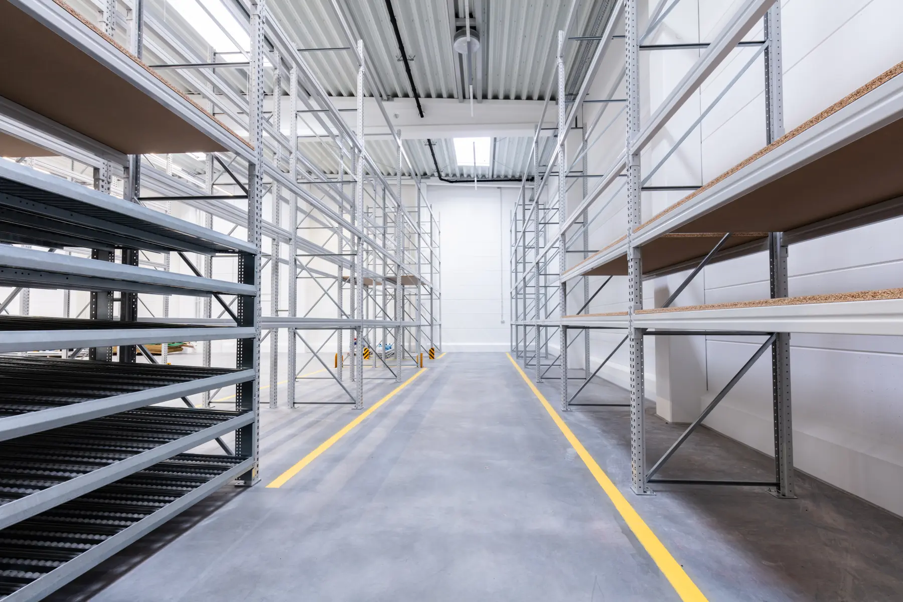 An empty warehouse aisle between steel racks