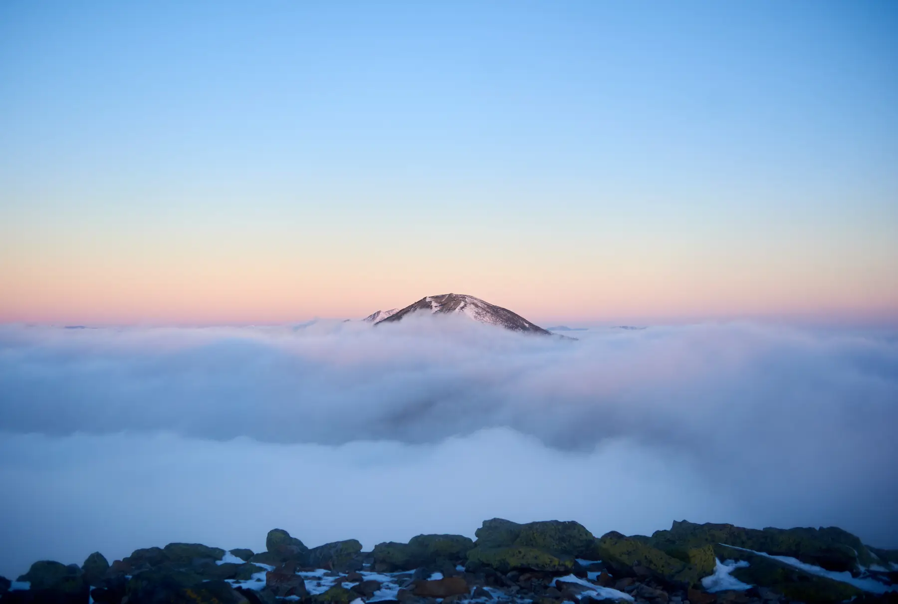 A mountain peak above a sea of cloud at dusk