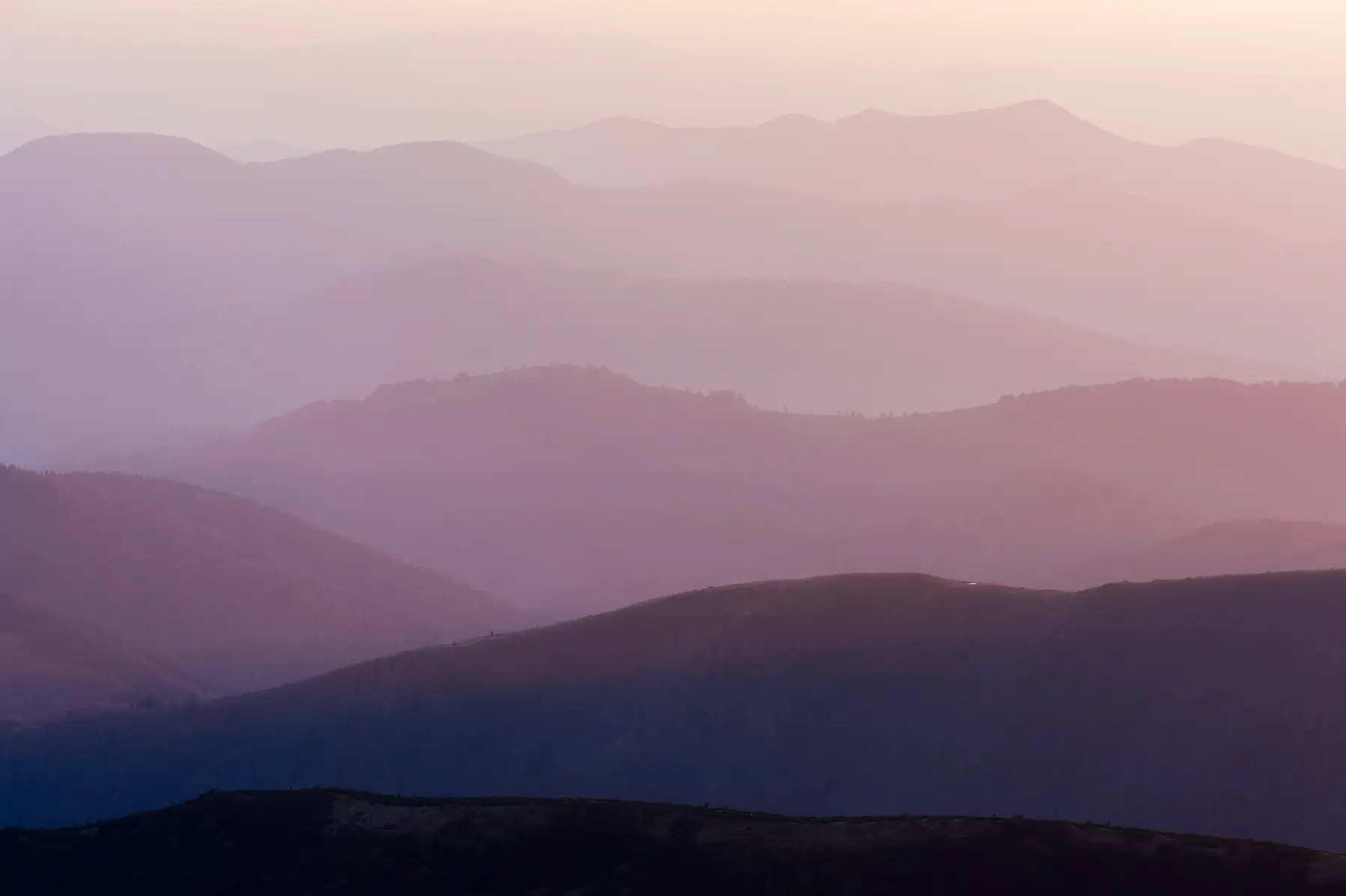 Layered mountain ranges in pink evening light